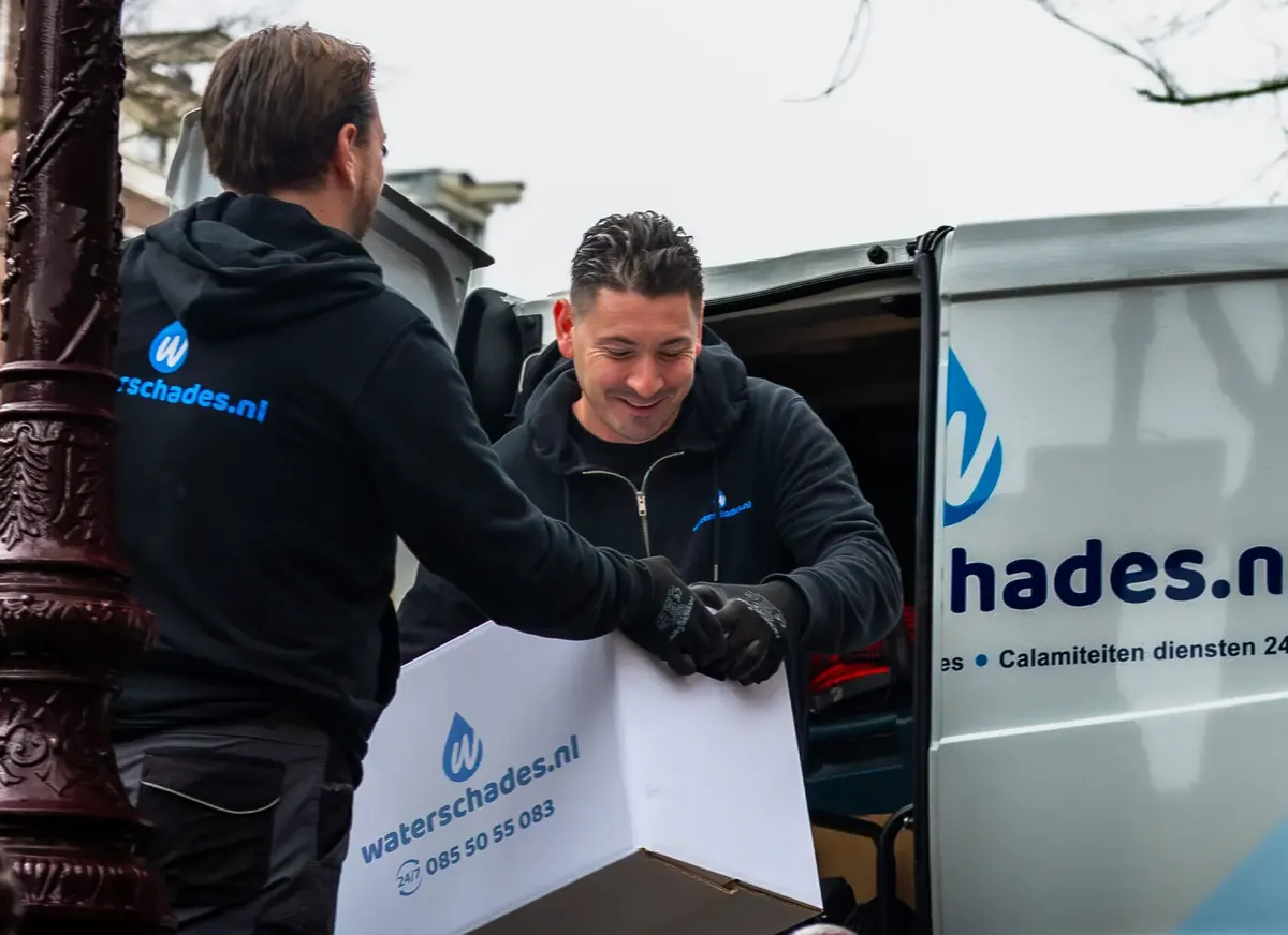 Twee medewerkers van Waterschades.nl halen materiaal uit de bus bij een pand